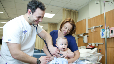 nursing student with nursing teacher using a stethoscope to listen to a babys heart